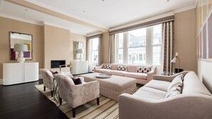 A modern living room with a sofa set, armchairs, a coffee table, and a television. - Kensington Luxury - 2 Bedrooms (London)