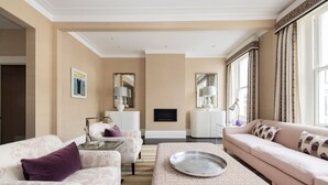 A living room with a sofa, armchairs, a coffee table, and a TV. - Kensington Luxury - 2 Bedrooms (London)
