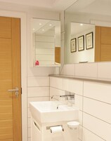 Un baño con un lavamanos blanco, un espejo y un inodoro.