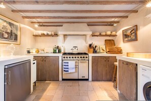 A kitchen with wooden cabinets, a stove, a dishwasher, and a washing machine. - London Living 3 Bedroom Home in Chelsea (London)