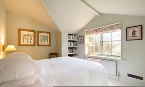 A bedroom with a bed, a bookshelf, framed botanical prints, and a window with a view. - London Living 3 Bedroom Home in Chelsea (London)