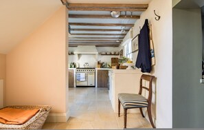 A narrow hallway leading to a kitchen with a wooden ceiling, a chair, and a wicker basket. - London Living 3 Bedroom Home in Chelsea (London)