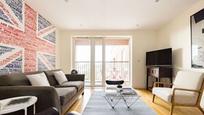 Una sala de estar moderna con un sofá, un sillón, un televisor y una pared con texto.