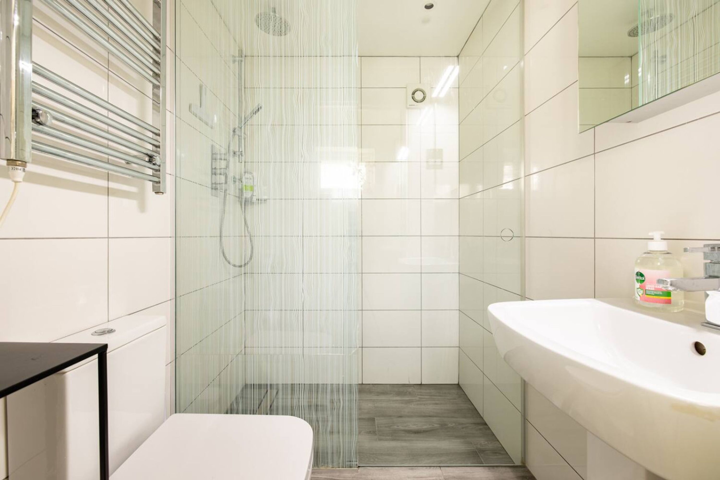 Une salle de bain moderne avec une douche à parois de verre, un lavabo blanc et un miroir.