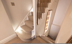 A staircase with a carpeted handrail and wooden steps. - Sunny in Chelsea Luxurious 3 Bedroom Chelsea Home (London)