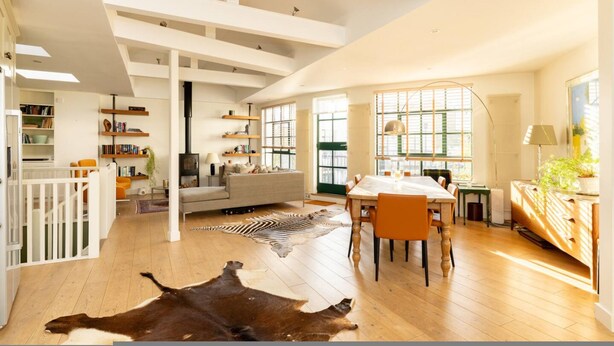 A spacious living area with a high ceiling, a dining table, and a large window. - A Gentle Riverside Charm 2 Bedroom Mews House (London)