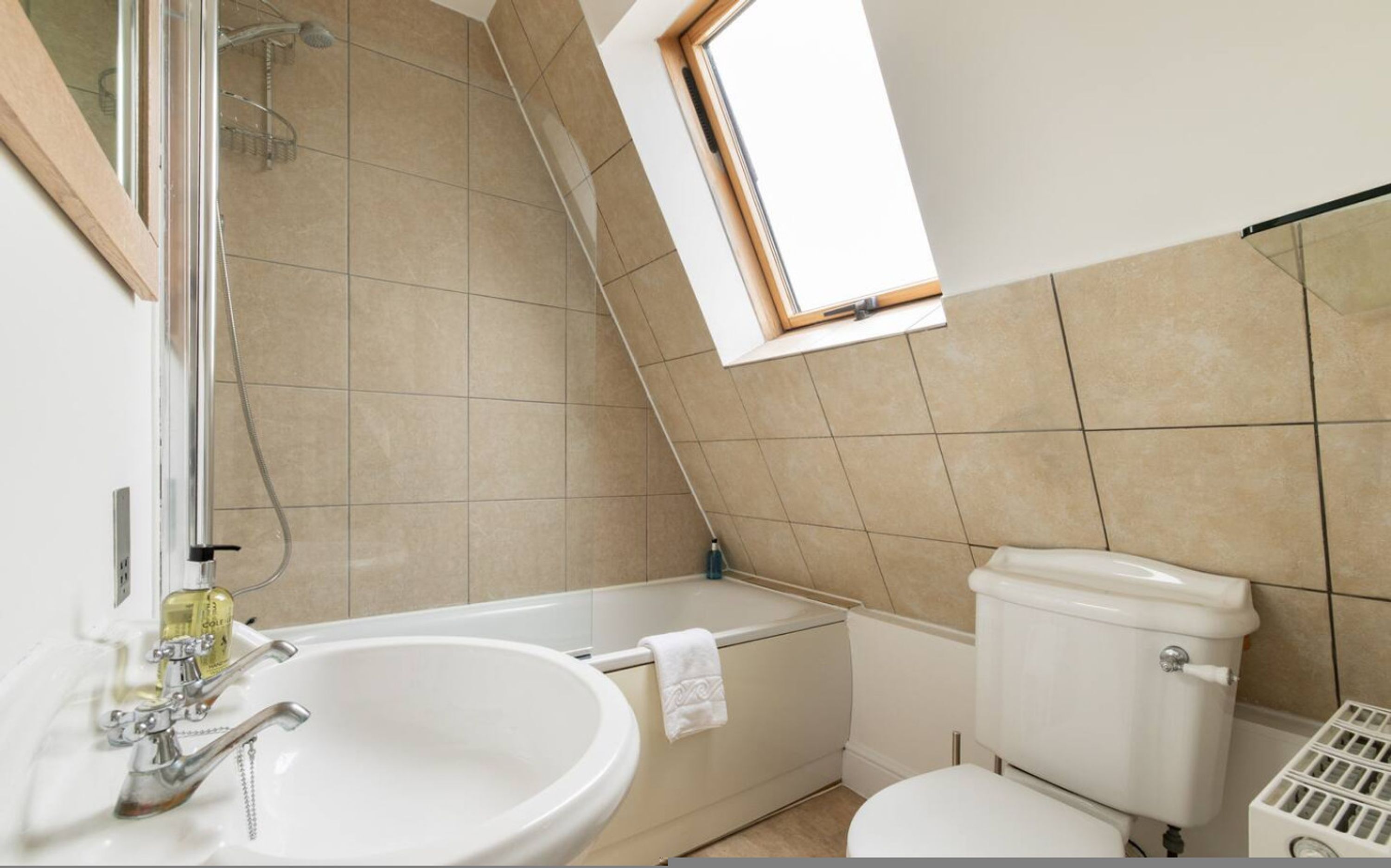 A bathroom with a bathtub, toilet, sink, and a window.
