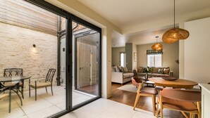 Un interior moderno con zona de comedor, un conjunto de sofás y un gran ventanal que da a un espacio exterior.