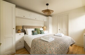 Ein Schlafzimmer mit Bett, Nachttischen, einer Pendelleuchte und einer Tür.