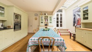 A kitchen with a dining table, chairs, cabinets, and a window. - Battersea Park 3 Bedroom House With Private Garden (London)