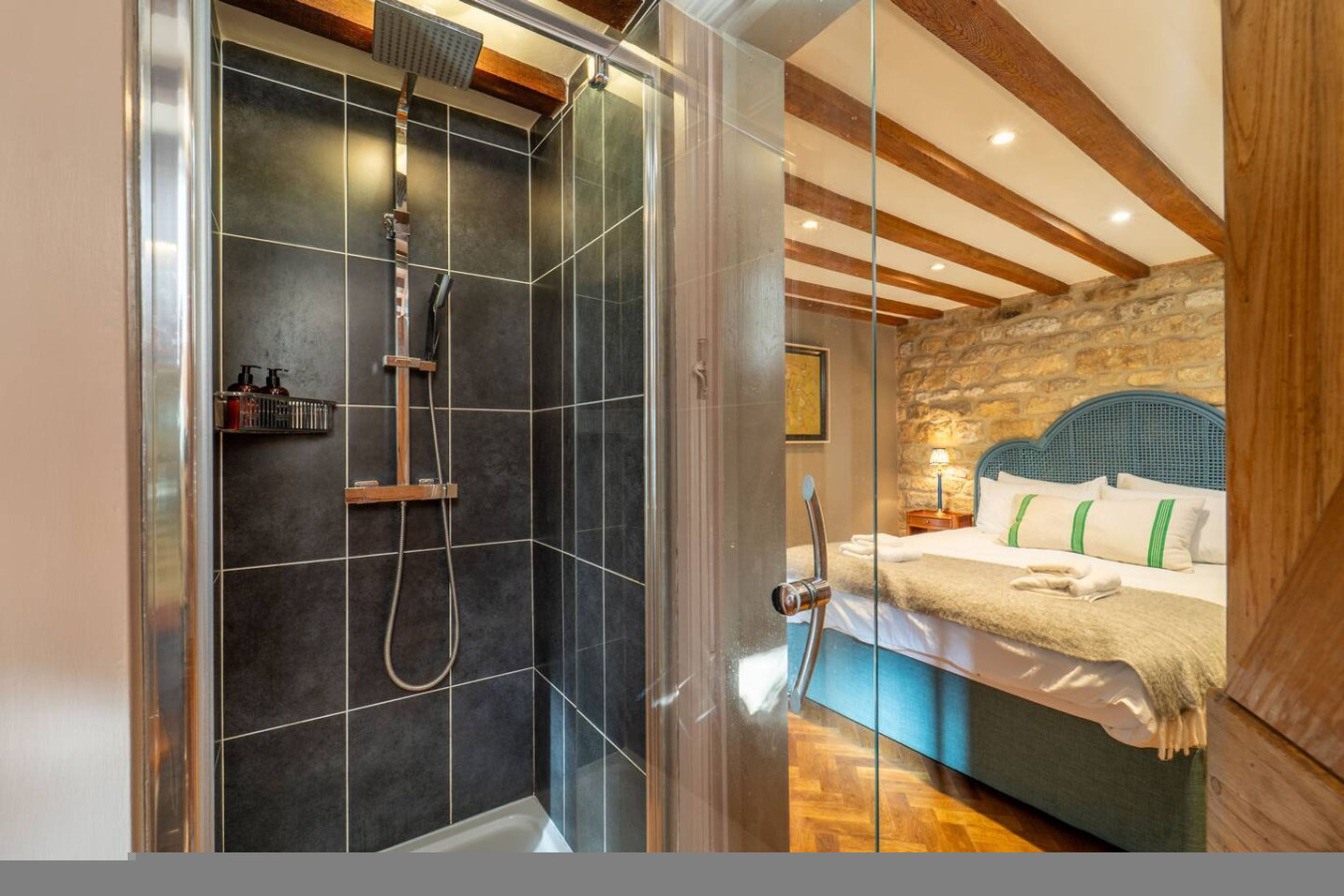 Een moderne badkamer met een glazen douchecabine, een houten plafond en een stenen muur.