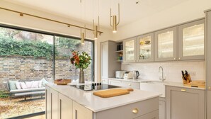Een moderne keuken met een groot eiland, inbouwapparatuur en uitzicht op een tuin.