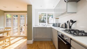A modern kitchen with a gas stove, sink, and cabinets. - The Thames Embrace 3 BR Garden House in Battersea (London)