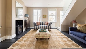 A living room with a fireplace, two sofas, a patterned rug, and a staircase. - The Thames Embrace 3 BR Garden House in Battersea (London)
