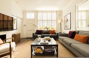 A living room with a sofa, coffee table, and a television. - Cobbled Charm 3 Bedroom House (London)