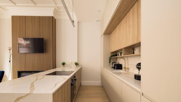 A modern kitchen with a marble countertop, wooden cabinetry, and a built-in TV. - London Lovers - Newly Refurbished 2 BR in Chelsea (London)
