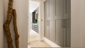 A hallway with a wooden sculpture, grey wardrobe with gold handles, and a carpeted floor. - London Lovers - Newly Refurbished 2 BR in Chelsea (London)
