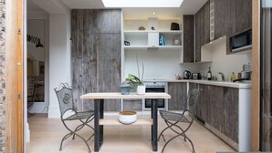 A modern kitchen with a central island, wooden cabinets, and a skylight. - Retreat to a Stylish 1 Bedroom Flat in Chelsea (London)