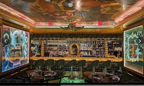 Eine Bar mit traditionellem asiatischen Design, die eine zentrale Drachenstatue, Holzmöbel und eine Decke mit aufwändigen Verzierungen zeigt.