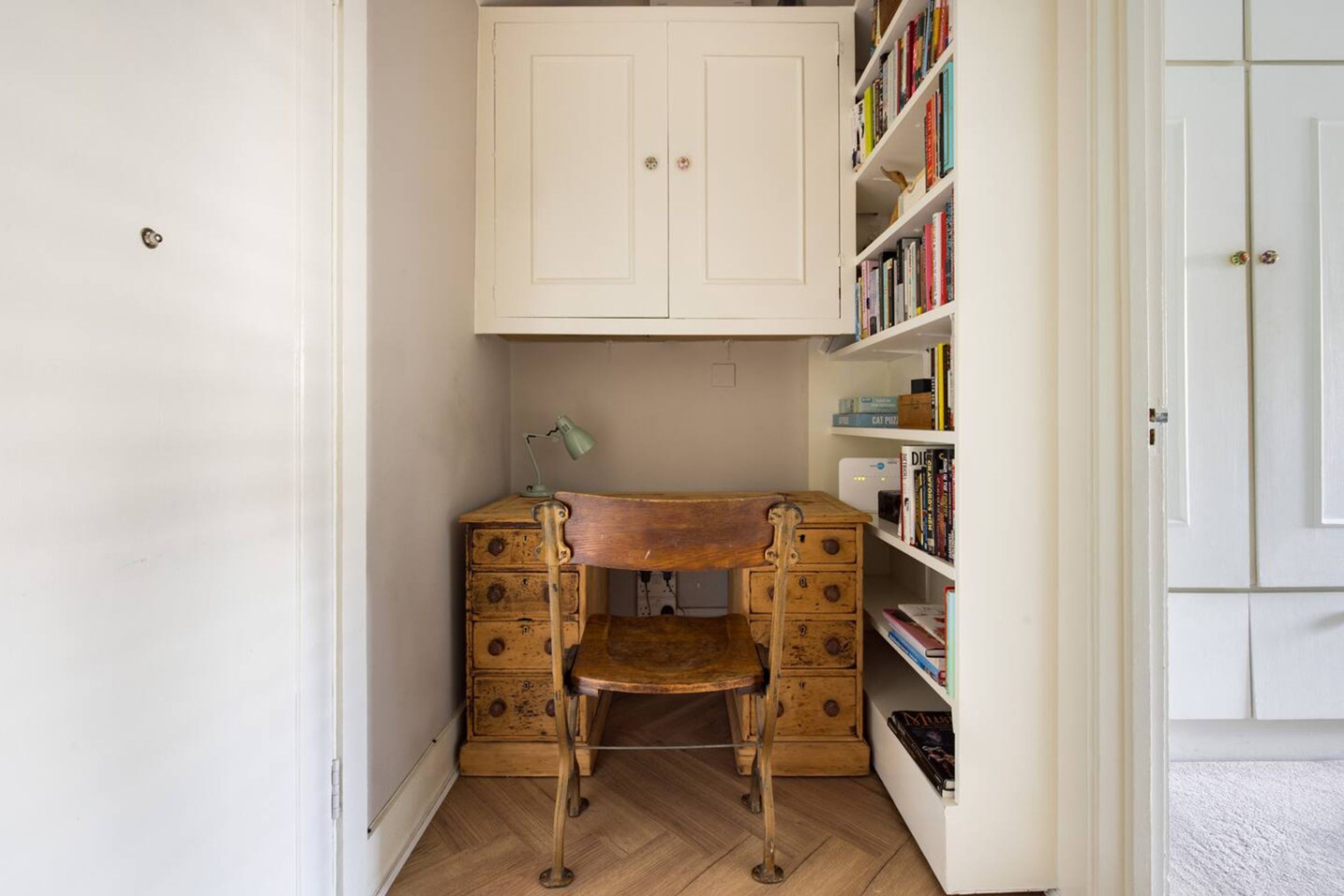 A study with a wooden desk, a chair, a lamp, and a bookshelf.