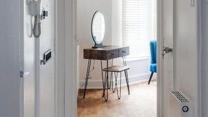 A hallway leading to a room with a desk, a mirror, and a window with blinds. - Stylish 1 BD in Notting Hill (London)
