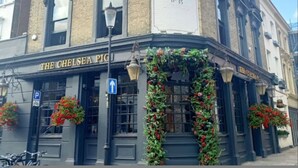 Un edificio en esquina con un letrero que dice 'The Chelsea Pig' y un cartel grande con la ilustración de un cerdo.