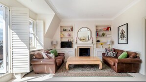 Una sala de estar con chimenea, dos sofás de cuero, una mesa de centro y una estantería.