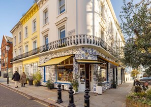Ein Eckgebäude mit einem geschwungenen Balkon, einem Laden Eingang und blauem Himmel.