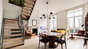 Ein modernes Wohnzimmer mit Treppe, einem runden Esstisch und einer Couch.
