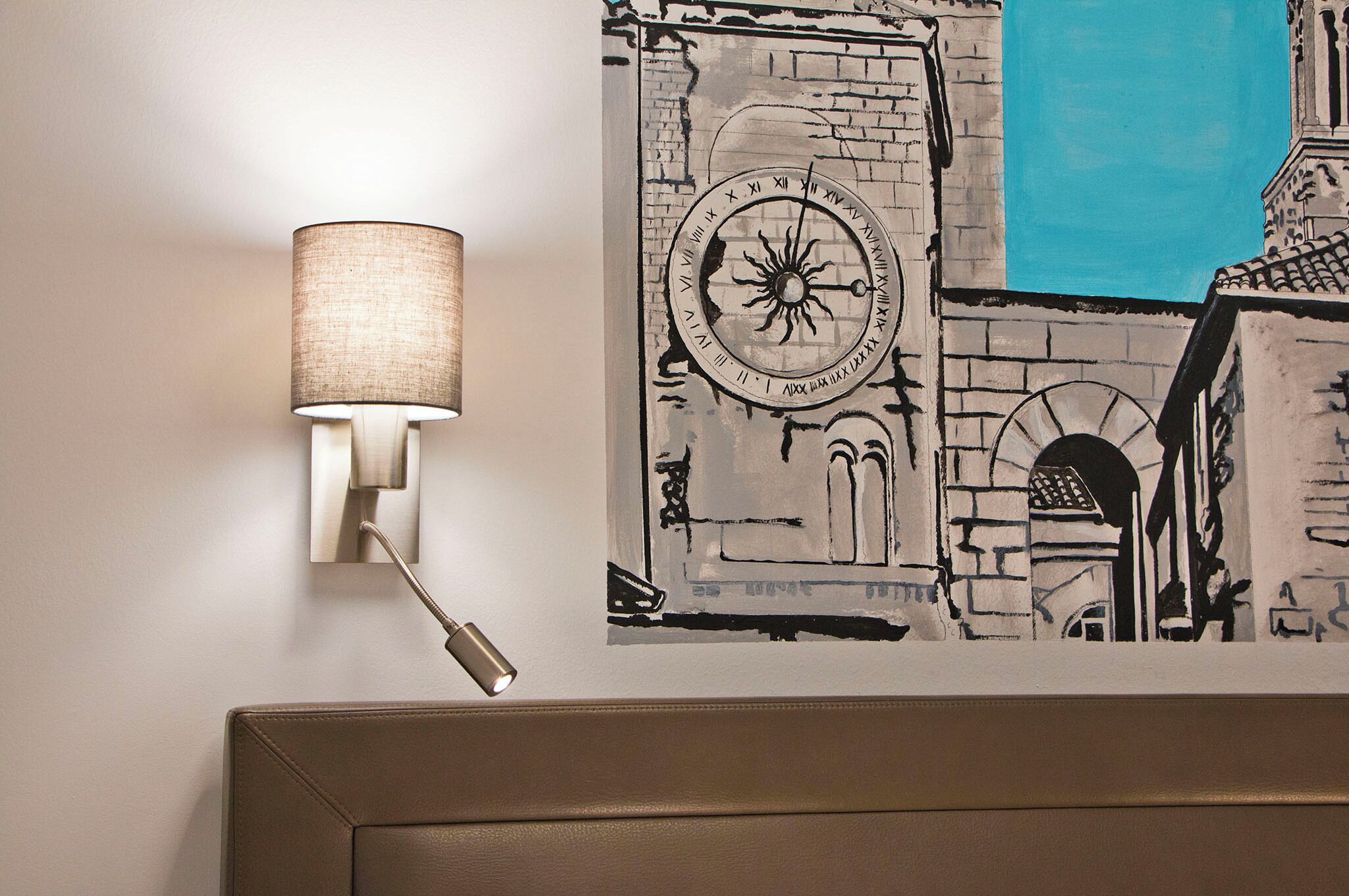 Una lámpara de pared, un reloj de pared y una vista parcial de la arquitectura de una habitación.