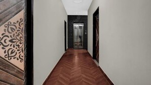 A hallway with a herringbone floor, a patterned wall on the left, and a door with a glass panel at the end.