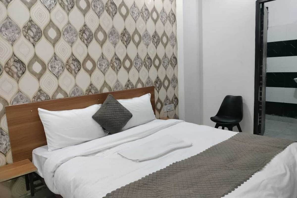 Un letto con testiera in legno, biancheria da letto bianca, una coperta marrone e una parete decorata.