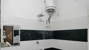 A bathroom with a black and white tiled wall, a white sink, and a shower head.