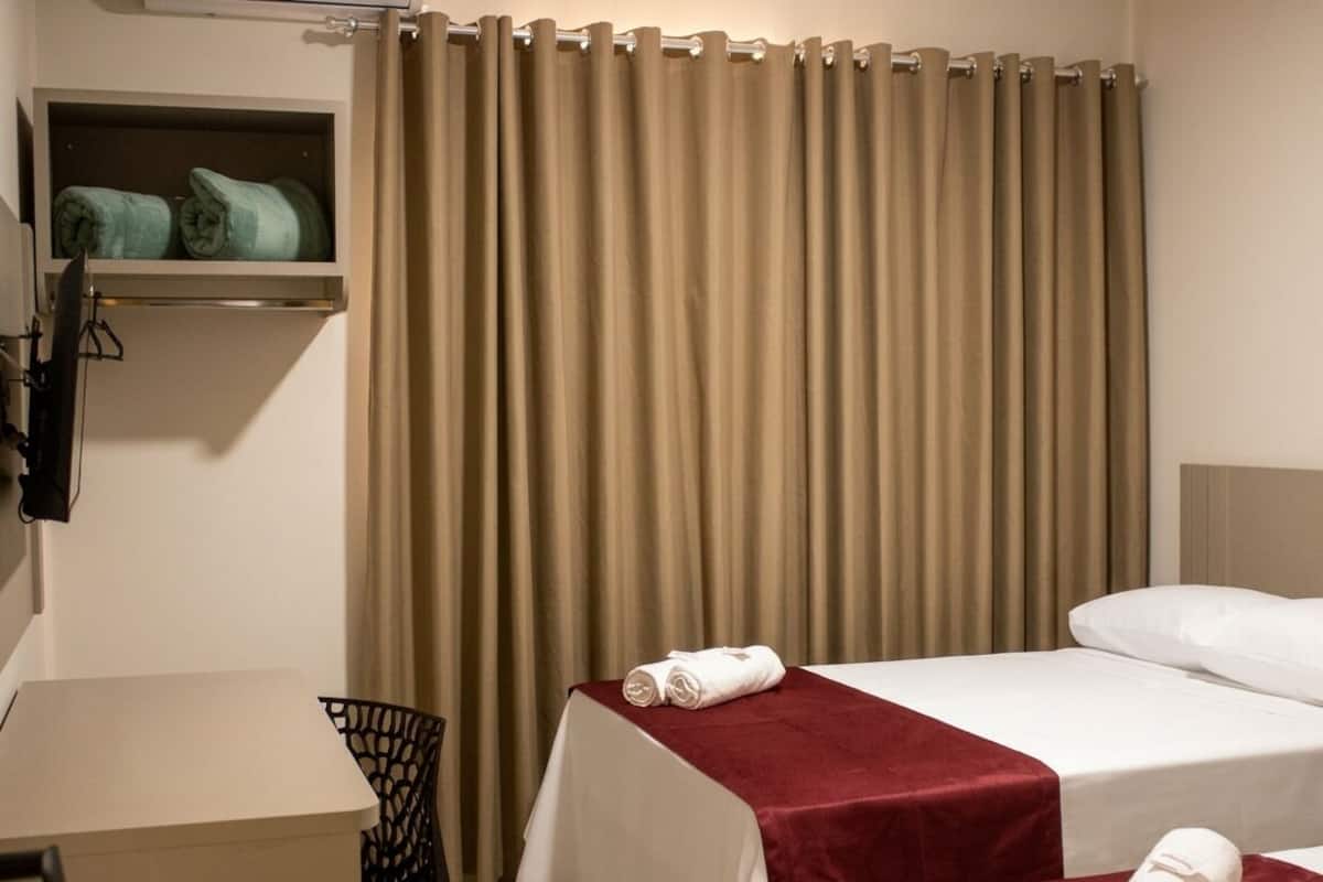 A hotel room with a bed, a desk, and a chair.