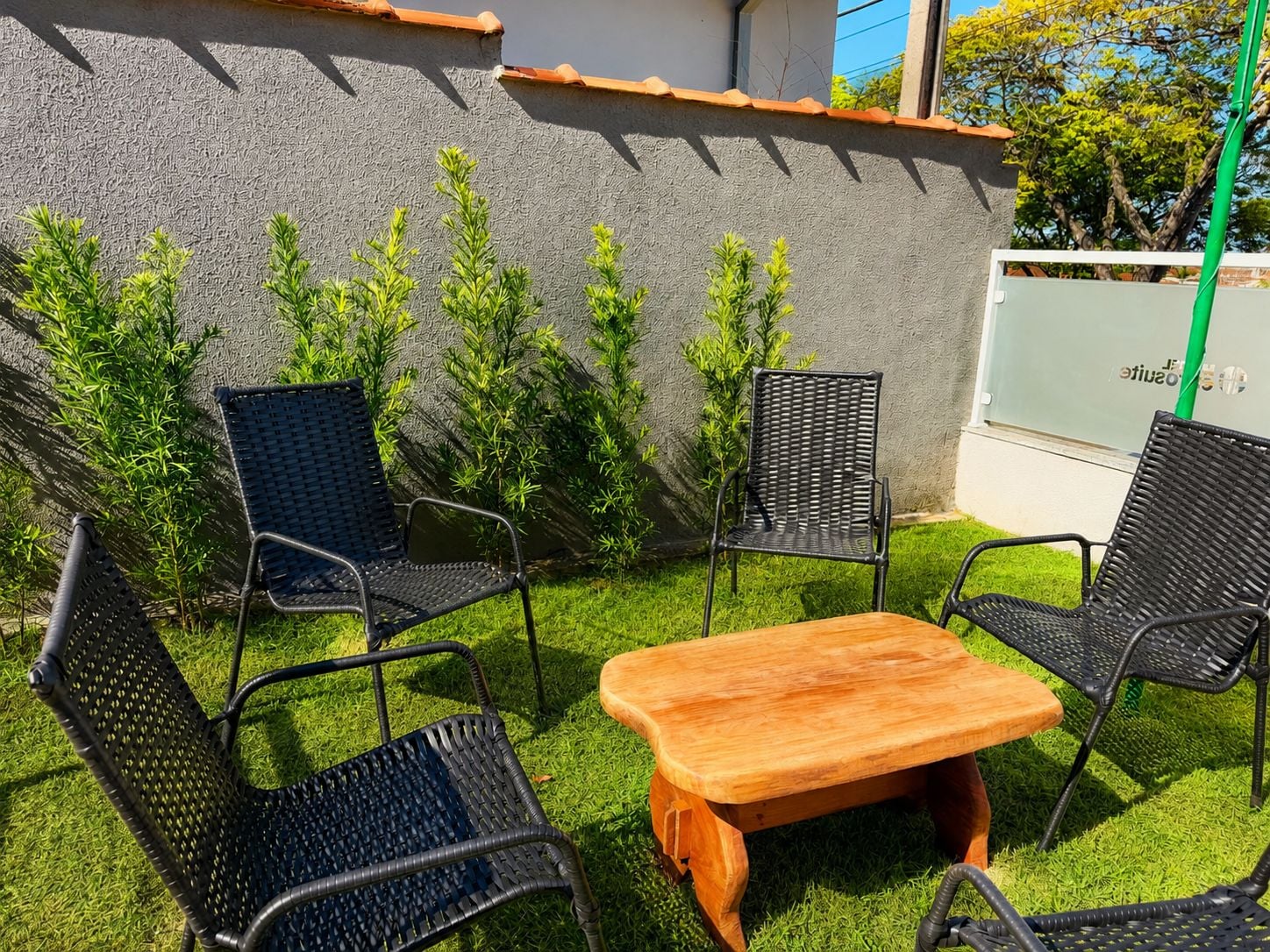 Eine Terrasse mit einem Holztisch und vier schwarzen Metallstühlen.