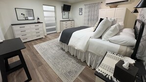 Een slaapkamer met een bed, een dressoir, een bureau en een airconditioning.