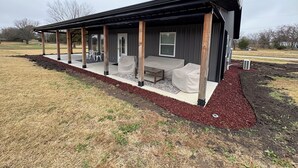 Een modern huis met een overdekte patio, een deur en een raam.