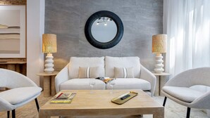 A modern living room with a sofa, two side tables, a coffee table, and a round mirror on the wall. - Elegant 3BD Apartment in Granada Buensuceso II (Granada)