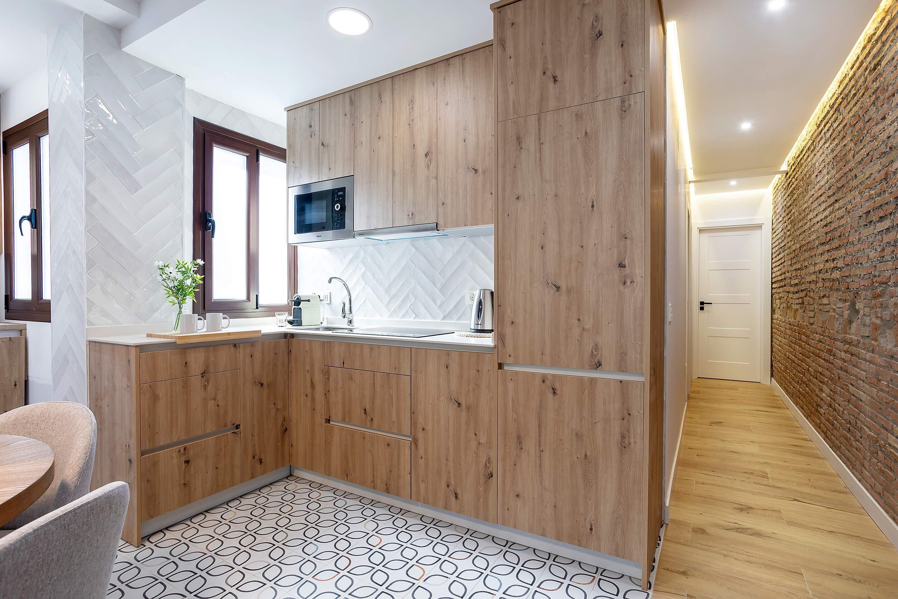 Une cuisine moderne avec des meubles en bois, un four à micro-ondes et un dosseret décoré d’un motif en chevrons.