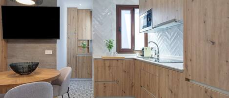 Uma cozinha moderna com armários de madeira, televisão de tela plana, mesa de jantar com cadeiras e piso estampado.