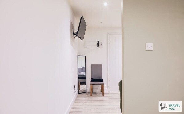 A hallway with a chair, a mirror, and a door. - Flora`s Flats Studio 2 (Nottingham)