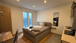 Un dormitorio moderno con sofá cama, escritorio y una silla.