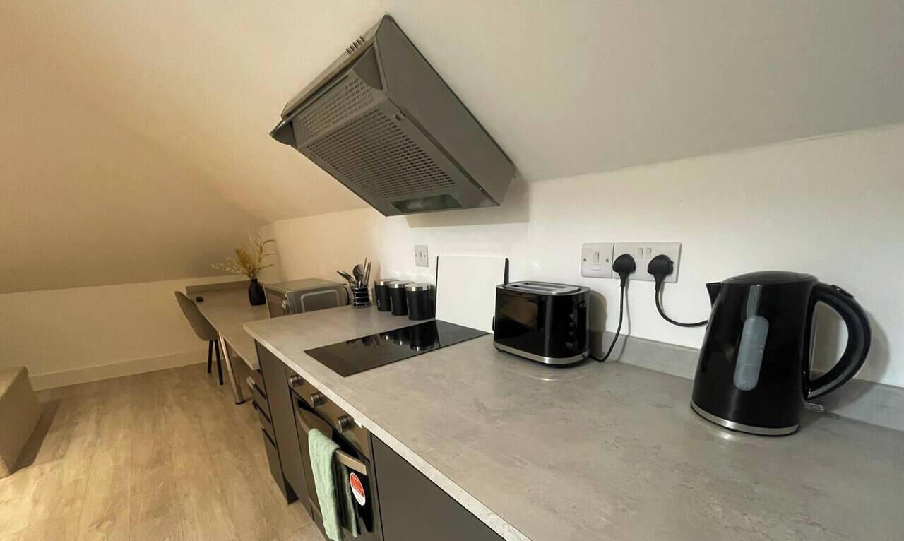 A modern kitchen with a built-in stove, a microwave, a kettle, and a toaster.