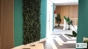 En hall med en vertikal trädgårdsvägg, träpanel och ett golv med ett sicksackmönster.