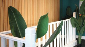 A white railing with large green leaves in front of a wooden wall. - Dojo House - Studio 10 (Nottingham)
