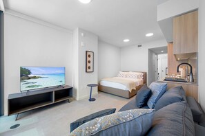 Ein modernes Schlafzimmer mit einem Bett, einem Fernseher und einer Couch.
