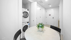 A modern room with a round table, chairs, a potted plant, and a washing machine. - NOK Urban Studio in Prime Miami Location (Miami)