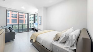 A modern hotel room with a large bed, a sofa, a desk, and a balcony with a city view. - NOK Urban Studio in Prime Miami Location (Miami)