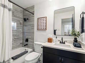 A modern bathroom with a shower, toilet, sink, and vanity. - Poolside Playhouse / Ultimate Game Room + Pool (The Colony)