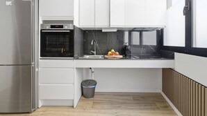 Et moderne køkken med et stålkøleskab, indbygget ovn og en vask med marmorbeklædt bagvæg.